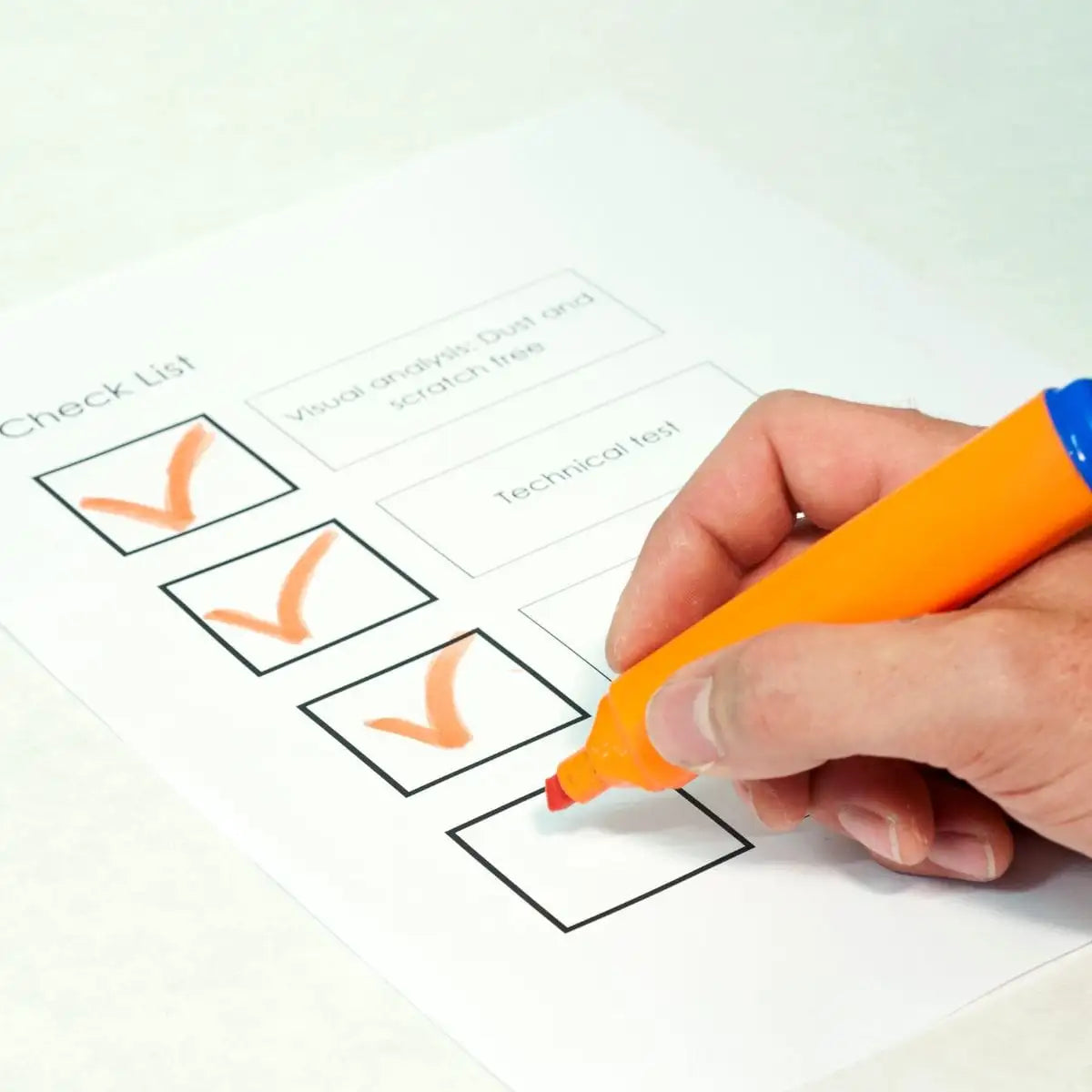 Surligneur orange avec un capuchon bleu utilisé pour marquer des cases cochées sur une liste de contrôle.